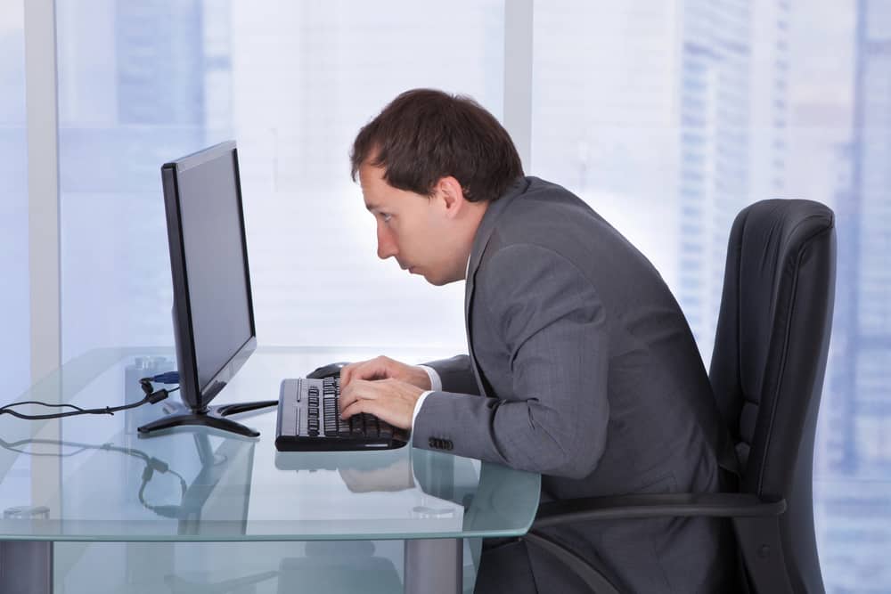 man with bad posture hunching over a computer desk