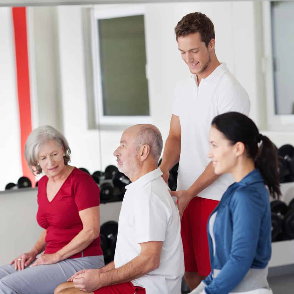 Chiropractor demonstrating for a man how to sit for best posture.